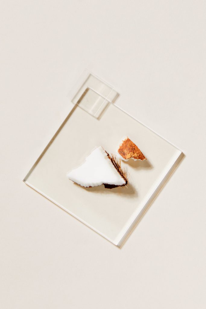 Coconut flakes with a dollop of cream on a small pale tile.